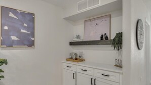 A kitchen with white cabinets, a wooden countertop, a hanging shelf, and a clock on the wall. - Gorgeous Sunny Home for Big Groups w/ Private Pool (Garland)