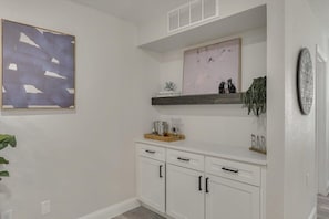 A kitchen with white cabinets, a wooden countertop, a hanging shelf, and a clock on the wall. - Gorgeous Sunny Home for Big Groups w/ Private Pool (Garland)