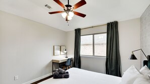 Ein Hotelzimmer mit Bett, Schreibtisch, Stuhl und Deckenventilator.