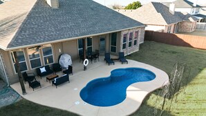 Ein Garten mit Swimmingpool, Gartenmöbeln und einer überdachten Terrasse.