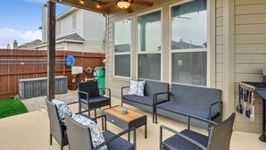 Eine überdachte Terrasse mit Korbmöbeln, Deckenventilator und Lichterketten.