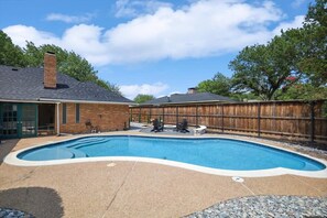 A backyard with a swimming pool, a brick house, and a wooden fence. - Allen Abode - 4 Bedrm. Pool, Fire Pit , Charm (Allen)