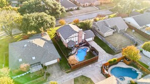 A residential area with a large house featuring a swimming pool, a fenced backyard, and a smaller pool in the front yard. - Prime Plano 4BR Home With Pool, Arcarde, Ping-pong (Plano)