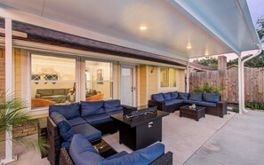 Eine Terrasse im Freien mit einer Eckcouch, einem Couchtisch und einem Feuerkorb.