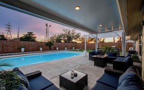 Eine überdachte Terrasse im Freien mit Pool, Sitzgelegenheit und Blick auf den Garten.