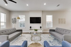 A modern living room with two sofas, a coffee table, a flat-screen TV, and artwork on the walls. - Modern and Spacious High End Home Near Downtown (Dallas)