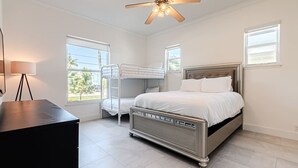 A bedroom with a bunk bed, a desk, a ceiling fan, and large windows. - Breathtaking 6BD Riverfront Mansion w Pool (Cape Coral)