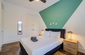 Ein Schlafzimmer mit Bett, Nachttischen, einem Kleiderschrank und einem Deckenventilator.