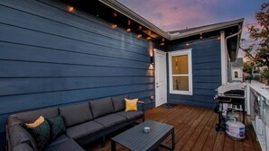 A deck with a sofa and table, a grill, and a gas tank. - 3BD Historic Charm x Modern Amenities w Hot Tub (Houston)