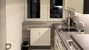 Ett modernt kök med en inbyggd spis, en vattenkokare och ett fönster.