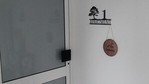Ett rum med en vit dörr, en skylt med texten ”Rökning förbjuden” och en skylt på väggen med texten ”1 lägenhet”.