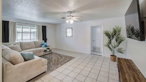 A spacious living room with a sofa, a coffee table, a ceiling fan, and a potted plant. - Heart of Houston - 3-bd Apartment (Houston)
