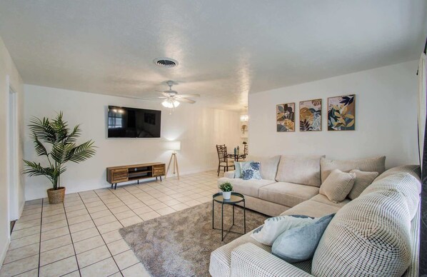 Ein Wohnzimmer mit Sofa, Fernseher, Deckenventilator und einem Kunstwerk an der Wand.