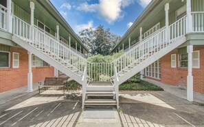 Ein Gebäude mit einer zentralen Treppe, flankiert von zwei Flügeln, wobei jede einen Balkon besitzt.
