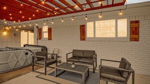 Una habitación con pared de ladrillo blanco, un sofá, una mesa de centro e hidromasaje.