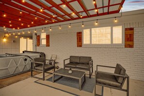 A room with a white brick wall, a sofa, a coffee table, and a hot tub. - 5BR Near At&t Stadium Pool, Hot Tub, Mini Golf (DeSoto)