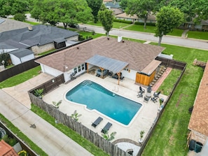 A residential backyard with a swimming pool, patio furniture, and a covered outdoor seating area. - 5BR Near At&t Stadium Pool, Hot Tub, Mini Golf (DeSoto)