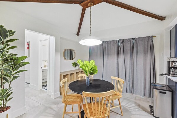 A dining area with a round table, wooden chairs, a hanging light fixture, and a coffee machine. - 5BR Near At&t Stadium Pool, Hot Tub, Mini Golf (DeSoto)