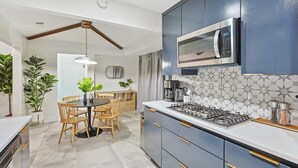 Una cocina moderna con armarios oscuros, una estufa a gas, un microondas y un comedor con mesa y sillas.