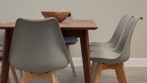 Un comedor con una mesa de madera, dos sillas y una lámpara de techo moderna.
