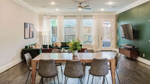 A dining area with a wooden table, six chairs, a ceiling fan, and a large window with curtains. - Houston Central Location - Stylish With Jacuzzi (Houston)