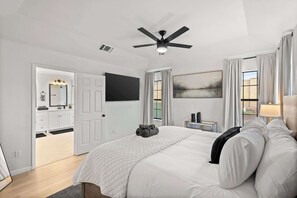 A bedroom with a bed, a ceiling fan, a painting, and a view of the outside. - Heart of Grand Prairie 3BD With Pool, Patio, BBQ (Grand Prairie)