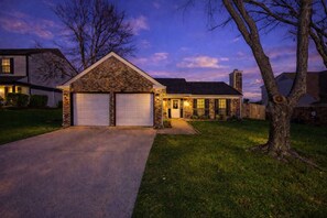 A two-story house with a stone facade, a garage, and a well-maintained lawn. - Heart of Grand Prairie 3BD With Pool, Patio, BBQ (Grand Prairie)