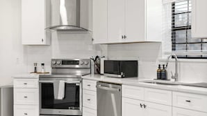 A modern kitchen with white cabinetry, stainless steel appliances, and a window with blinds. - Heart of Grand Prairie 3BD With Pool, Patio, BBQ (Grand Prairie)