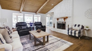 A spacious living room with a high ceiling, a fireplace, and a large window. - Highland Village - 4BR w Backyard Pool Oasis (Lewisville)