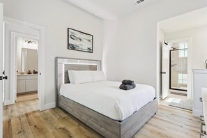 Ein Schlafzimmer mit Bett, Dusche, Badezimmer und einem Flur, der in eine Küche führt.