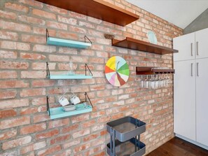 Une cuisine avec des murs en briques, des étagères, un décor en forme de diagramme circulaire et un meuble blanc.