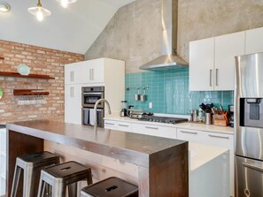 A modern kitchen with a central island, stainless steel appliances, and a blue-tiled backsplash. - 3-bd/2-ba Northern Dallas Retreat Hot Tub & bbq (Dallas)