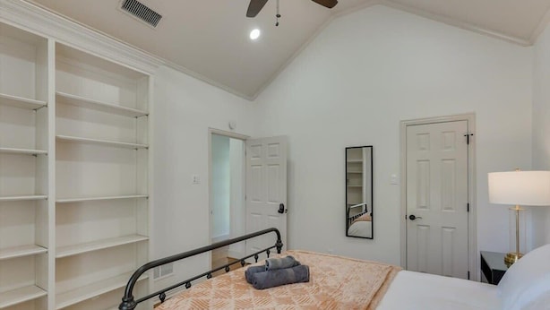 Ein Schlafzimmer mit Bett, Kleiderschrank, Spiegel und Deckenventilator.