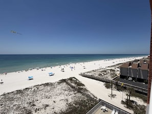 Ein Strand mit blauem Himmel, sandigem Ufer und einem Gebäude mit flachem Dach.