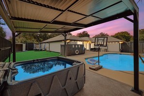 A backyard with a hot tub, a pool, and a basketball hoop under a covered area. - Plano Perfect Getaway - Pool, Hot Tub, BBQ Grill (Plano)