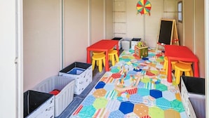 A children's playroom with colorful hexagonal mats, two red tables, yellow stools, and a chalkboard. - Plano Perfect Getaway - Pool, Hot Tub, BBQ Grill (Plano)