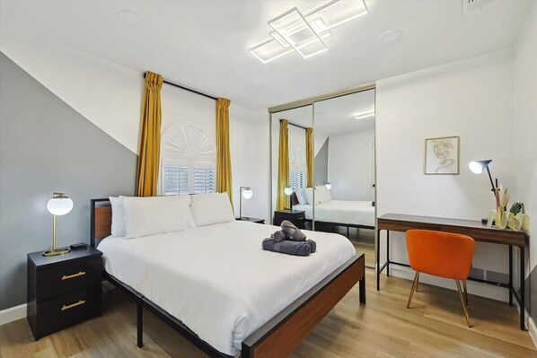 Ein modernes Hotelzimmer mit Bett, Nachttischen, Schreibtisch und Stuhl.