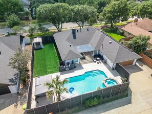 A residential backyard with a swimming pool, a hot tub, and a covered patio area. - Plano Perfect Getaway - Pool, Hot Tub, BBQ Grill (Plano)