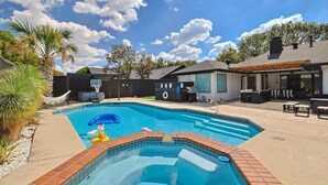 A swimming pool with a brick edge, surrounded by a patio area with outdoor furniture and a covered seating area. - Plano Perfect Getaway - Pool, Hot Tub, BBQ Grill (Plano)