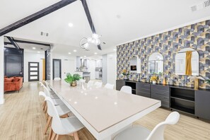 A modern kitchen with a large island, white cabinetry, and a patterned backsplash. - Plano Perfect Getaway - Pool, Hot Tub, BBQ Grill (Plano)