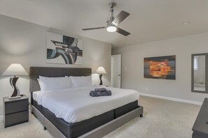 A bedroom with a bed, two bedside tables, a ceiling fan, and artwork on the walls. - Spacious and Modern Home With Private Pool (Plano)