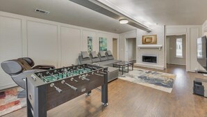 Una sala de estar moderna con mesa de fútbol, un sofá, chimenea y televisor.