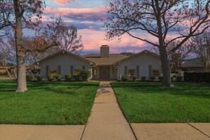 A two-story house with a symmetrical front, a central chimney, and a well-maintained lawn. - Spacious and Modern Home With Private Pool (Plano)