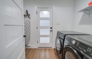 Ein Waschraum mit einer Waschmaschine mit Frontlader, einer Tür mit satinierten Glasfeldern und einer Wand mit Muster.