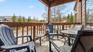 A wooden deck with chairs and a table, overlooking a mountainous landscape. - Breck Getaway | Trails, Balcony & Shared Hot Tub (Breckenridge)