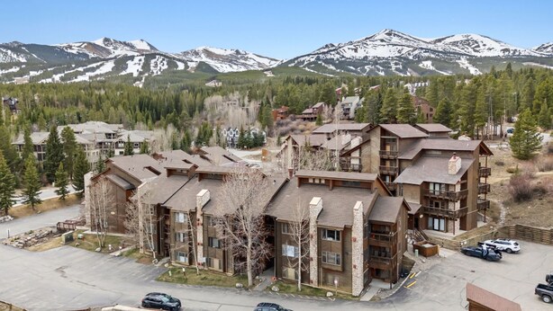 A multi-story lodge with a stone facade, multiple balconies, and a parking area. - Breck Getaway | Trails, Balcony & Shared Hot Tub (Breckenridge)