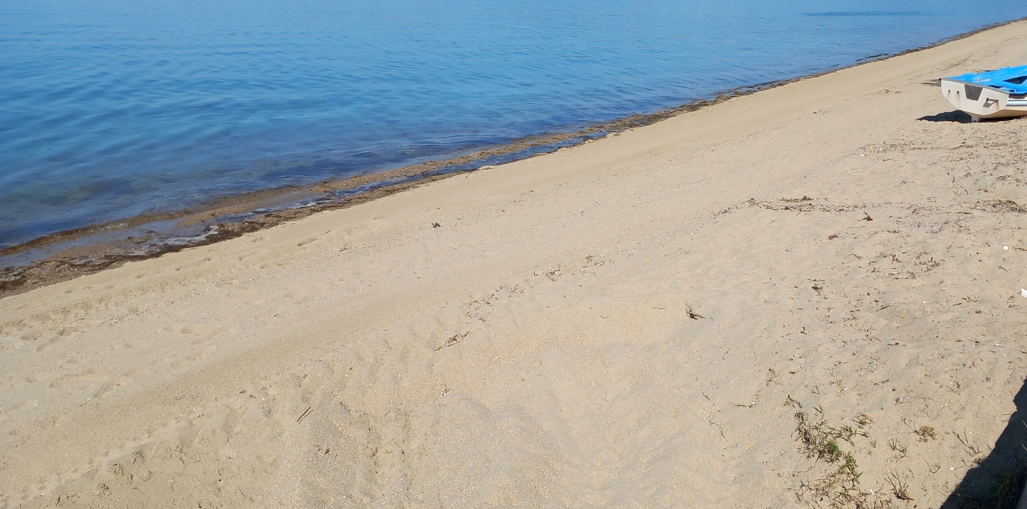 En sandstrand med en båd til højre.