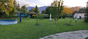 A well-maintained garden with a swimming pool, trees, and a clear view of mountains in the background.