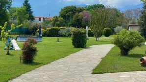 A garden with a stone pathway, small bushes, and a statue.