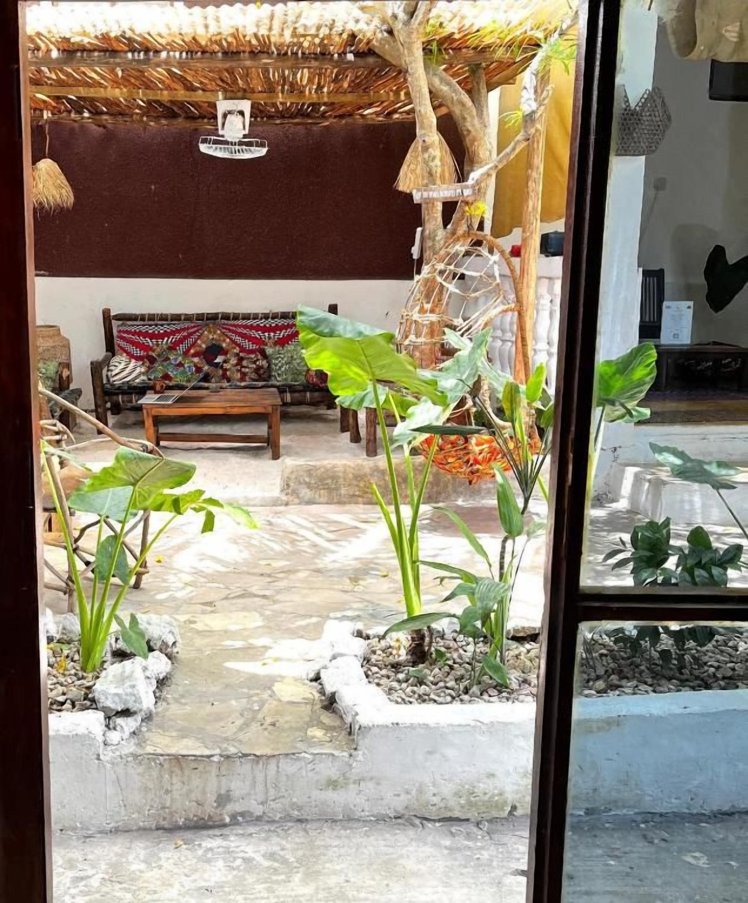 Una habitación con techo de paja, un sofá con cojines estampados y plantas en macetas.